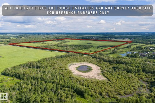 Expansive land parcel featuring a large open field, surrounded by diverse natural landscapes including mature trees and wetlands - 23327 Twp Rd 510, Rural Leduc County, AB 