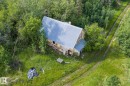 Rural property featuring a metal roof, wood-sided exterior, and a surrounding natural landscape with mature trees - 23327 Twp Rd 510, Rural Leduc County, AB 