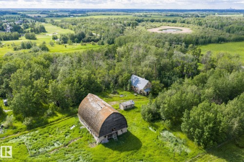 Expansive rural property featuring a large gambrel-roof barn, a secondary structure, and dense mature tree cover - 23327 Twp Rd 510, Rural Leduc County, AB 