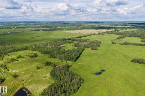 Expansive green acreage featuring dense tree lines and open fields - 23327 Twp Rd 510, Rural Leduc County, AB 