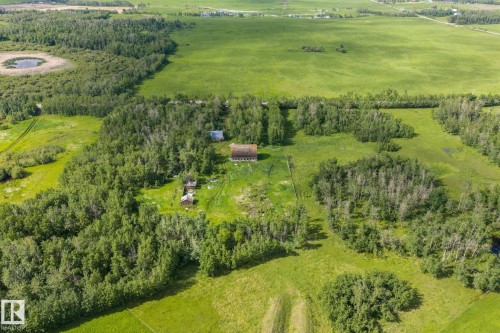 Expansive rural property featuring a primary residence, multiple outbuildings, mature tree coverage, open green spaces, and a natural pond - 23327 Twp Rd 510, Rural Leduc County, AB 