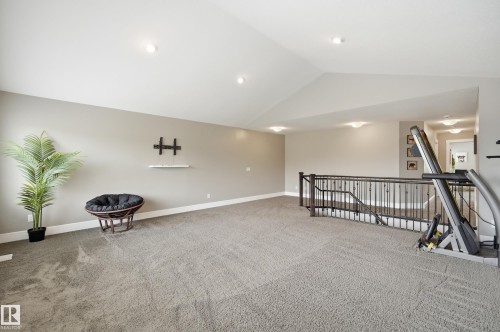 Spacious upper-level loft featuring vaulted ceilings, recessed lighting, and soft grey carpeting - 5430 Edworthy Way, Edmonton, AB - Indoor Photo Showing Other Room