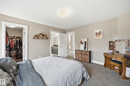 Carpeted bedroom featuring a walk-in closet with built-in shelving, a neutral color palette, and a semi-flush mount ceiling light - 5430 Edworthy Way, Edmonton, AB - Indoor Photo Showing Bedroom