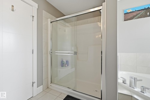 Shower enclosure featuring clear glass sliding doors and white tile surround - 5430 Edworthy Way, Edmonton, AB - Indoor Photo Showing Bathroom