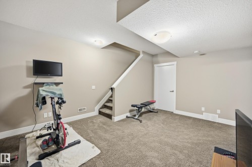 Carpeted lower level with neutral wall tones, white trim, and white doors - 5430 Edworthy Way, Edmonton, AB - Indoor Photo Showing Gym Room