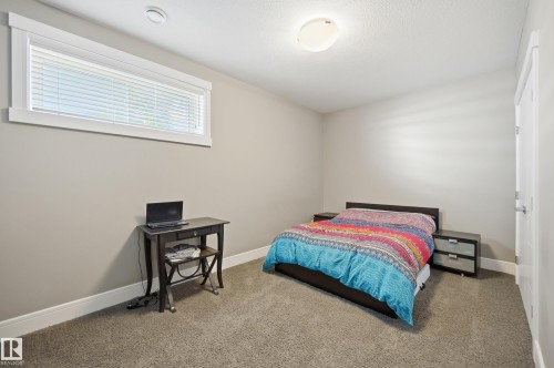 Neutral-toned interior room featuring a horizontal window with white blinds, light gray wall paint, and gray carpet flooring - 5430 Edworthy Way, Edmonton, AB - Indoor Photo Showing Bedroom