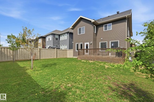 Expansive backyard featuring a manicured lawn, full privacy fencing, and a large wooden deck - 5430 Edworthy Way, Edmonton, AB - Outdoor