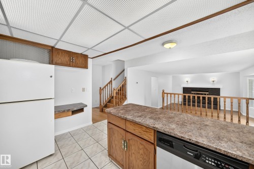 Kitchen area featuring white ceramic tile flooring and wood-finish cabinetry - 9843 188 Street, Edmonton, AB 