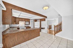 Kitchen featuring wood-finish cabinetry, a white tile backsplash, and a built-in double sink - 