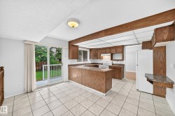 Kitchen space featuring wood cabinetry, white tile flooring, and a white tile backsplash - 
