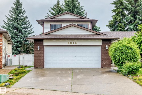 Two-story residence featuring a two-car garage with white door, brick accents, and neutral siding - 9843 188 Street, Edmonton, AB 