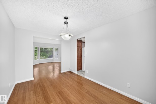 Dining area featuring wood-finish flooring and a central pendant light fixture - 9843 188 Street, Edmonton, AB 