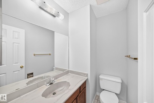 Bathroom vanity featuring a single basin, light-toned countertop, and wood-finish cabinetry - 9843 188 Street, Edmonton, AB 