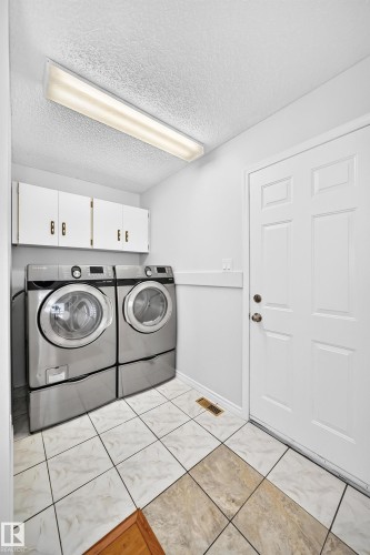Laundry area with white cabinetry, a white paneled door, and two-tone tile flooring - 9843 188 Street, Edmonton, AB 