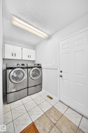 Laundry area with white cabinetry, a white paneled door, and two-tone tile flooring - 