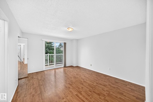 Spacious room featuring wood-finish flooring, light-colored walls, and a ceiling-mounted light fixture - 9843 188 Street, Edmonton, AB 