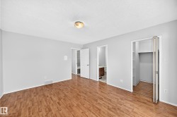 Spacious room featuring wood-finish flooring, light gray wall paint, and a textured white ceiling - 