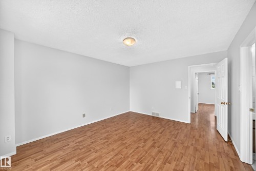 Spacious room featuring wood-finish flooring, light gray walls, white baseboards, and a ceiling-mounted light fixture - 9843 188 Street, Edmonton, AB 