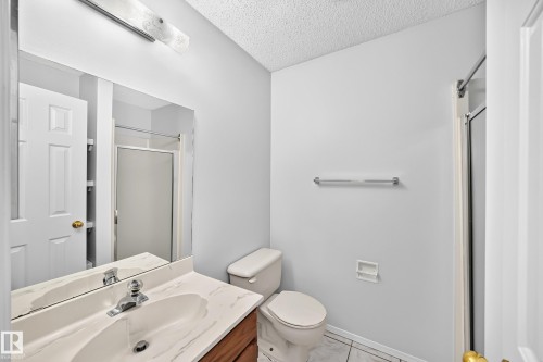 Bathroom featuring a wood-finish vanity with a white countertop, an integrated sink, and a chrome faucet - 9843 188 Street, Edmonton, AB 