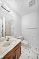 Bathroom featuring a wood-finish vanity with a built-in sink, a wall-mounted mirror, ceramic tile flooring, and a shower with a sliding glass door - 