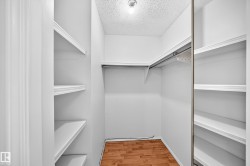 Walk-in closet featuring wood-finish flooring, built-in shelving, and a hanging rod - 