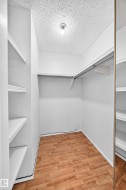 Walk-in closet featuring wood-finish flooring, built-in shelving, and a clothing rod with overhead storage - 