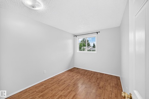 Room featuring light gray walls, wood-finish flooring, and a white trim package - 9843 188 Street, Edmonton, AB 