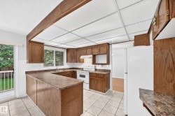 Kitchen featuring U-shaped cabinetry with wood-finish doors, a white tile backsplash, and a double-basin stainless steel sink - 