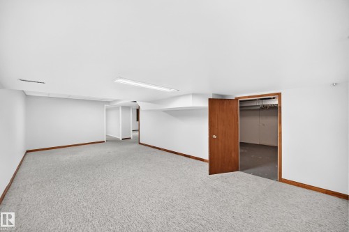 Spacious interior room featuring light-colored carpeting, white walls, and wood-finish baseboards - 9843 188 Street, Edmonton, AB 