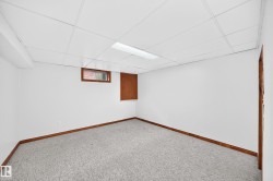 Carpeted room featuring white walls, wood-finish baseboards, and a drop ceiling with recessed lighting - 