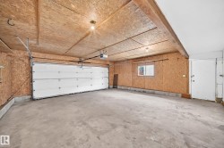 Spacious garage featuring a concrete floor, plywood walls, and a white paneled garage door - 