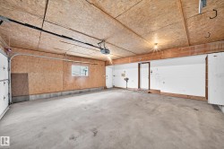 Spacious garage featuring a concrete floor, exposed wood ceiling, and built-in shelving - 