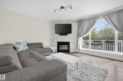 Living area featuring wood-finish flooring and a corner fireplace with a stacked stone facade - 
