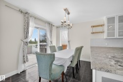 Dining area featuring a modern chandelier, dark tile flooring, and sliding glass doors opening to an exterior deck - 