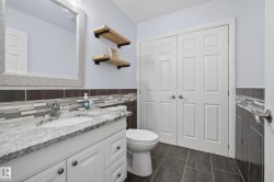 Bathroom featuring a white vanity with a light-toned countertop, a matching undermount sink, and a framed mirror - 