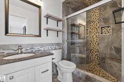 Modern bathroom featuring a glass-enclosed shower with pebble-tile detailing and a built-in bench - 