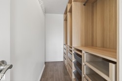 Custom closet system featuring light wood-finish shelving, integrated drawers, and metal hanging rods - 