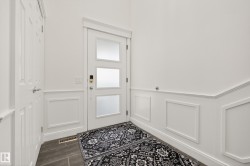 Entryway featuring a white door with frosted glass panels, an electronic key lock, and wainscoting with decorative molding - 