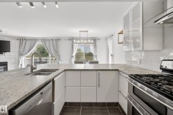 Modern kitchen featuring light-toned countertops, white flat-panel cabinetry, a stainless steel gas range, and a subway tile backsplash - 