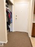 Entryway featuring a solid core door with brass hardware, textured carpeting, and a built-in closet with shelving and a hanging rod - 38 11265 31 Avenue, Edmonton, AB 