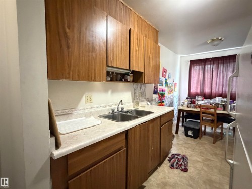 Kitchen featuring wood-finish cabinetry, a double basin stainless steel sink, and light-toned countertops - 38 11265 31 Avenue, Edmonton, AB 