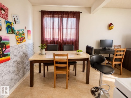 Dining area featuring a tiled floor, light wall color, and a window with sheer red curtains - 38 11265 31 Avenue, Edmonton, AB 