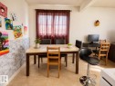 Dining area featuring a tiled floor, light wall color, and a window with sheer red curtains - 38 11265 31 Avenue, Edmonton, AB 