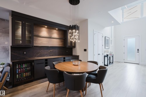 Dining area featuring a built-in cabinetry system with glass-front uppers, a beverage refrigerator, and dark countertop with integrated backsplash - 1313 Clement Crest, Edmonton, AB 