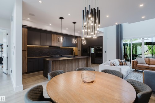 Gourmet kitchen featuring a waterfall island, custom cabinetry, integrated appliances, and a full-height stone backsplash - 1313 Clement Crest, Edmonton, AB 