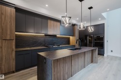 Modern kitchen featuring a waterfall island with an undermount sink and matte black faucet, dark flat-panel cabinetry, wood-finish accent cabinetry, and a black slab backsplash with veining - 