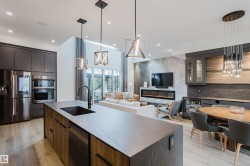 Spacious kitchen island with an integrated sink and matte black faucet, surrounded by contemporary cabinetry and stainless steel appliances - 
