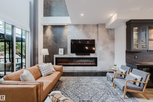 Living area featuring a floor-to-ceiling tiled fireplace surround, an integrated linear electric fireplace, and high ceilings - 1313 Clement Crest, Edmonton, AB 
