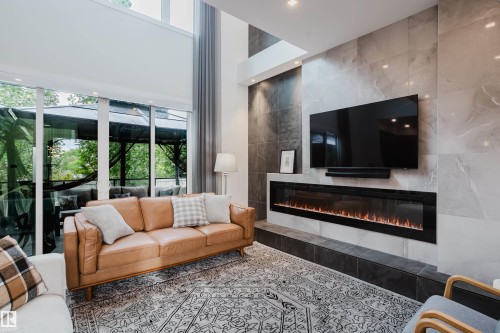 Spacious living area featuring a full-height tiled fireplace wall, an elongated linear fireplace, and recessed lighting - 1313 Clement Crest, Edmonton, AB 