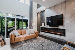 Spacious living area featuring a full-height tiled fireplace wall, an elongated linear fireplace, and recessed lighting - 